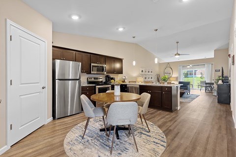 A modern kitchen with a dining table and chairs in the middle.