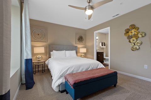 A bedroom with a bed, nightstand, and a ceiling fan.