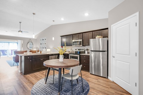 A modern kitchen with a round wooden table and a stainless steel refrigerator.