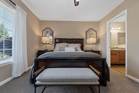 A bedroom with a large bed and two lamps on either side of the bed.