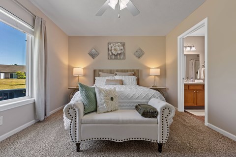 A bedroom with a bed, two lamps, and a ceiling fan.
