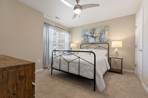 A bedroom with a bed, nightstand, and a painting on the wall.