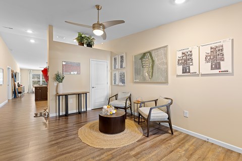 A living room with a brown rug and a ceiling fan.