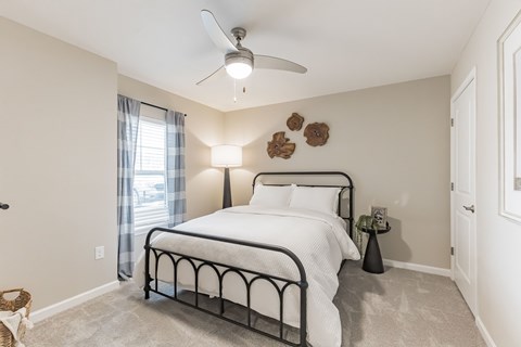 A bedroom with a large bed and a ceiling fan.