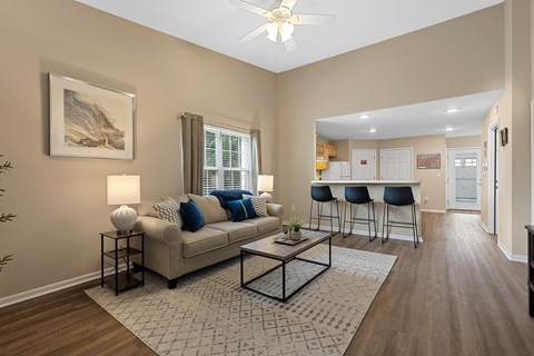 A living room with a beige couch, a coffee table, and a painting on the wall.