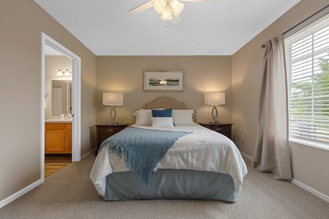 A bedroom with a bed, two lamps, and a ceiling fan.
