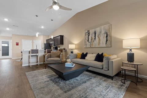A modern living room with a grey couch, a coffee table, and a painting on the wall.