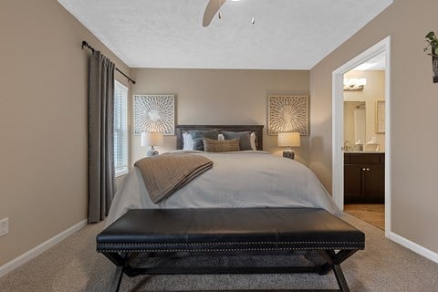 A bedroom with a large bed and a black bench.
