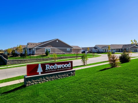 A sign for Redwood Apartment Neighborhood in front of some houses.