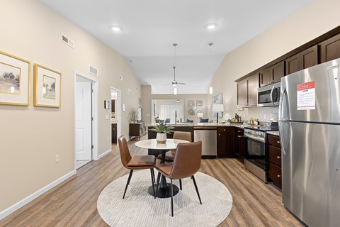 A modern kitchen with a dining table and chairs in the middle.