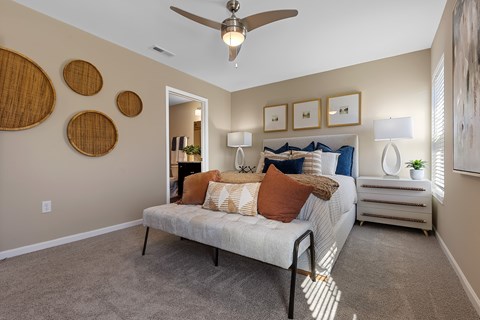 A bedroom with a bed, a ceiling fan, and a nightstand.