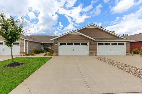 A house with a brown roof and two garages.