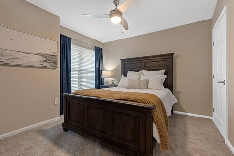 A bedroom with a large bed and a ceiling fan.