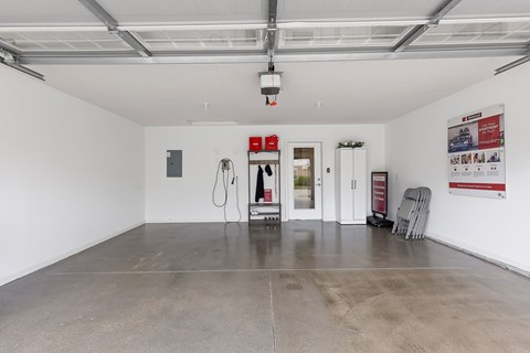 A spacious room with a concrete floor and white walls, equipped with a charging station and a refrigerator.