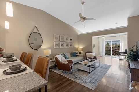 A modern dining room with a table set for six and a fan on the ceiling.