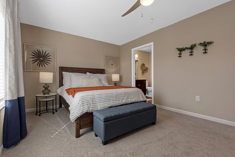 A bedroom with a large bed and a bench.