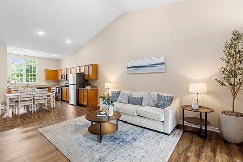 A living room with a white couch, a coffee table, and a dining table with chairs.