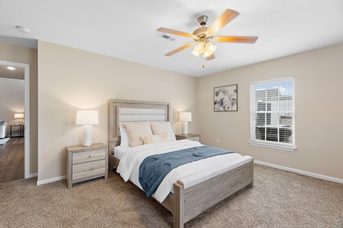 A bedroom with a bed, nightstands, and a ceiling fan.