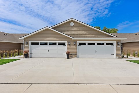 A two-car garage with a tan house in the background.