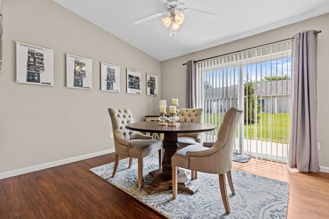 A dining room with a table set for four and a view of the backyard.