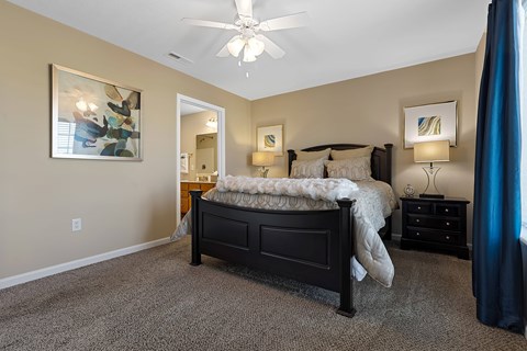 A bedroom with a bed, nightstand, and a ceiling fan.