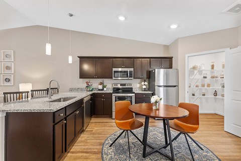 A modern kitchen with a table and chairs in the middle.