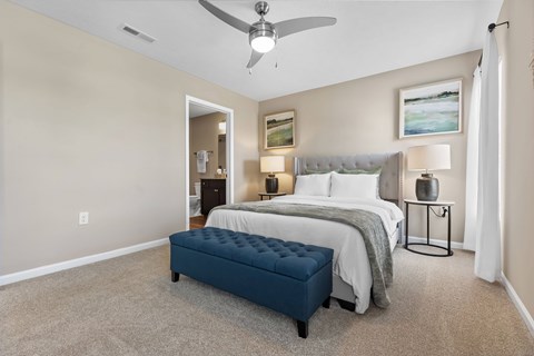 A bedroom with a bed, nightstand, and a fan.