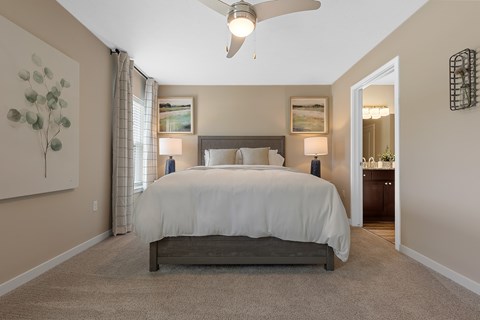 A bedroom with a large bed and a ceiling fan.