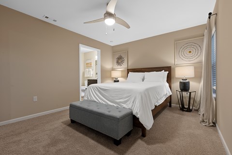 A bedroom with a large bed and a ceiling fan.