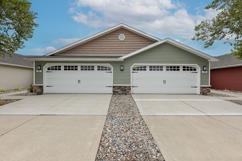 A house with two garages and a gravel driveway.