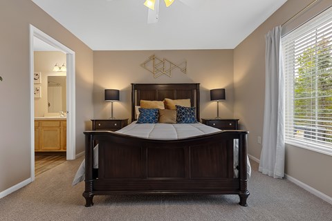 A bedroom with a large bed and two lamps.