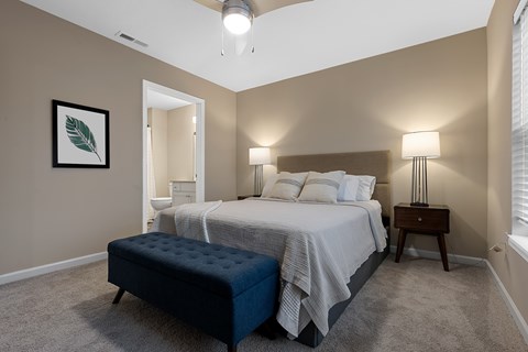 A bedroom with a bed, nightstand, and a framed leaf picture on the wall.