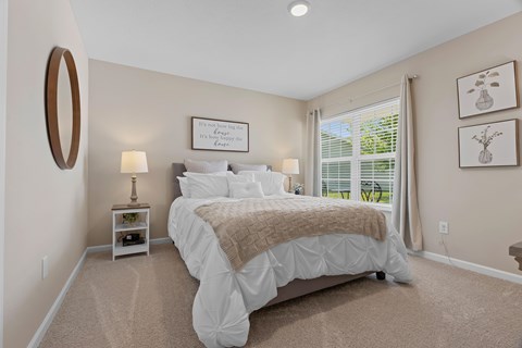 A bedroom with a large bed and a window with blinds.