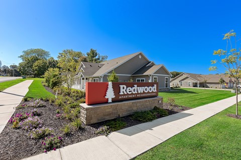A sign for Redwood Apartment is in front of a building.