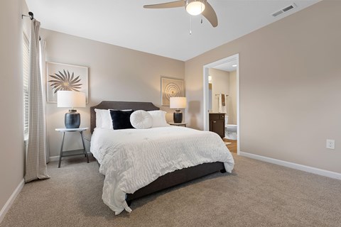 A bedroom with a large bed and a ceiling fan.