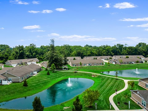 A residential area with a fountain in the middle of a grassy area.