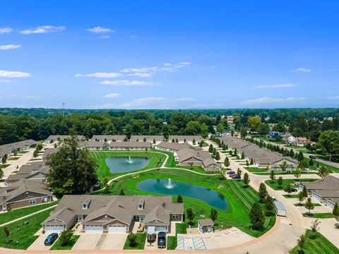 A bird's eye view of a residential neighborhood with houses, a pond, and a playground.