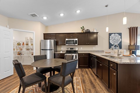 A kitchen with brown cabinets and a table with chairs.