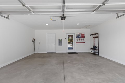 A spacious room with a white ceiling and walls, a grey floor, and a few pieces of furniture.