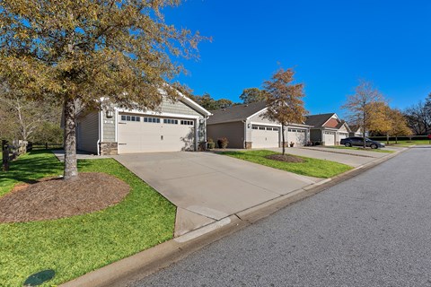 A residential street with a house and a tree in the foreground.