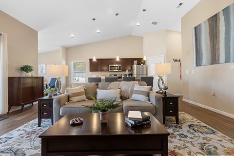 A modern living room with a dark wood coffee table and a large painting on the wall.