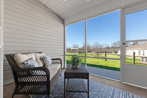 A patio with a sofa and a table with a view of a field.