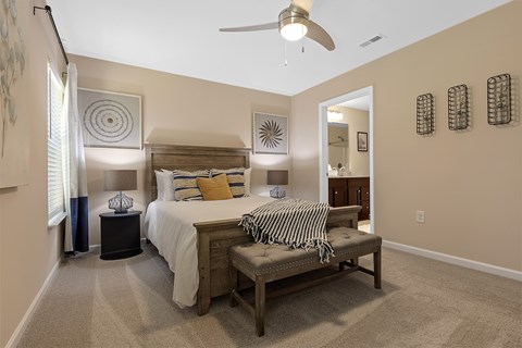 A bedroom with a bed, bench, and decorative wall art.