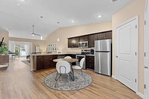 A modern kitchen with a dining table and chairs in the middle.