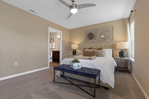 A bedroom with a bed, nightstand, and a ceiling fan.