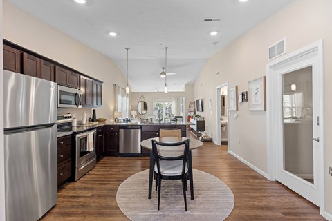 A modern kitchen with a dining table and chairs in the middle.