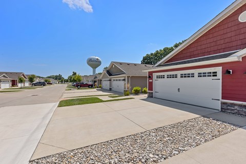 A red building with a white garage door is in front of a water tower.