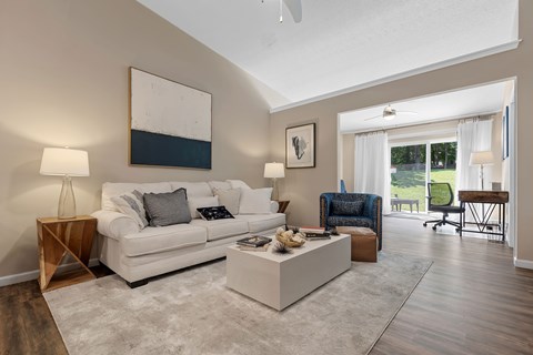 A living room with a white couch, a coffee table, and a painting on the wall.