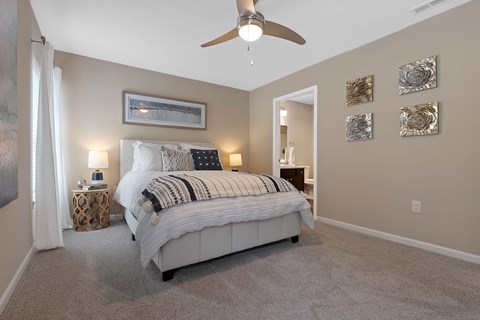 A bedroom with a large bed and a ceiling fan.