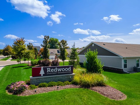 A sign for Redwood Apartment Homes is in front of a building.